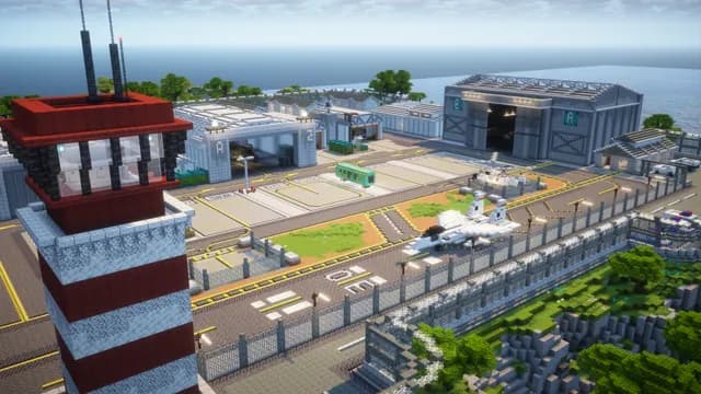 La base militaire vue depuis sa tour de contrôle rouge et blanche : hangars numérotés, piste et clôture